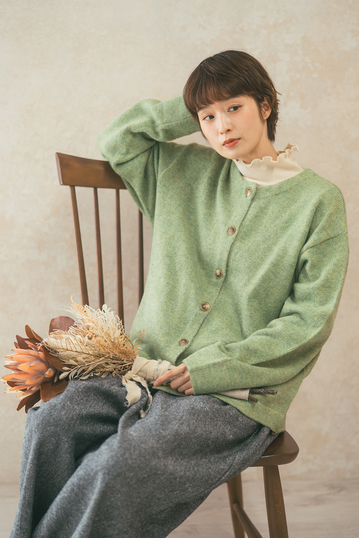 グリーンのカーディガンを着た女性モデルの写真